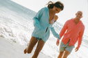 Woman in blue sweater and Man in coral sweater runing on the beach